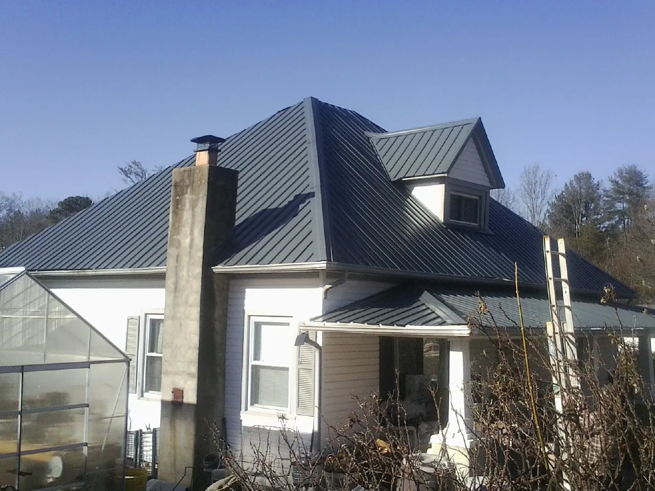 Dark blue standing seam metal roof on a white farmhouse with dormer — Slate & Tile Roof Repair by Roofing Brothers in White Sulphur Springs