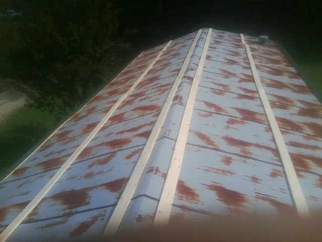 Rusted metal roof panels with new wood purlins before replacement — Storm Damage Roof Repair in White Sulphur Springs by Roofing Brothers