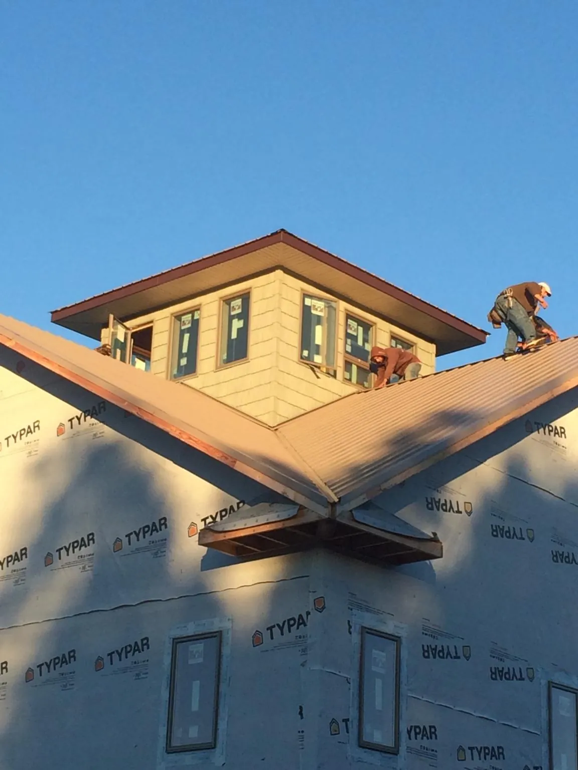 Roofers working around a rooftop cupola on a new metal roof at sunset — Roof Waterproofing in White Sulphur Springs by Roofing Brothers